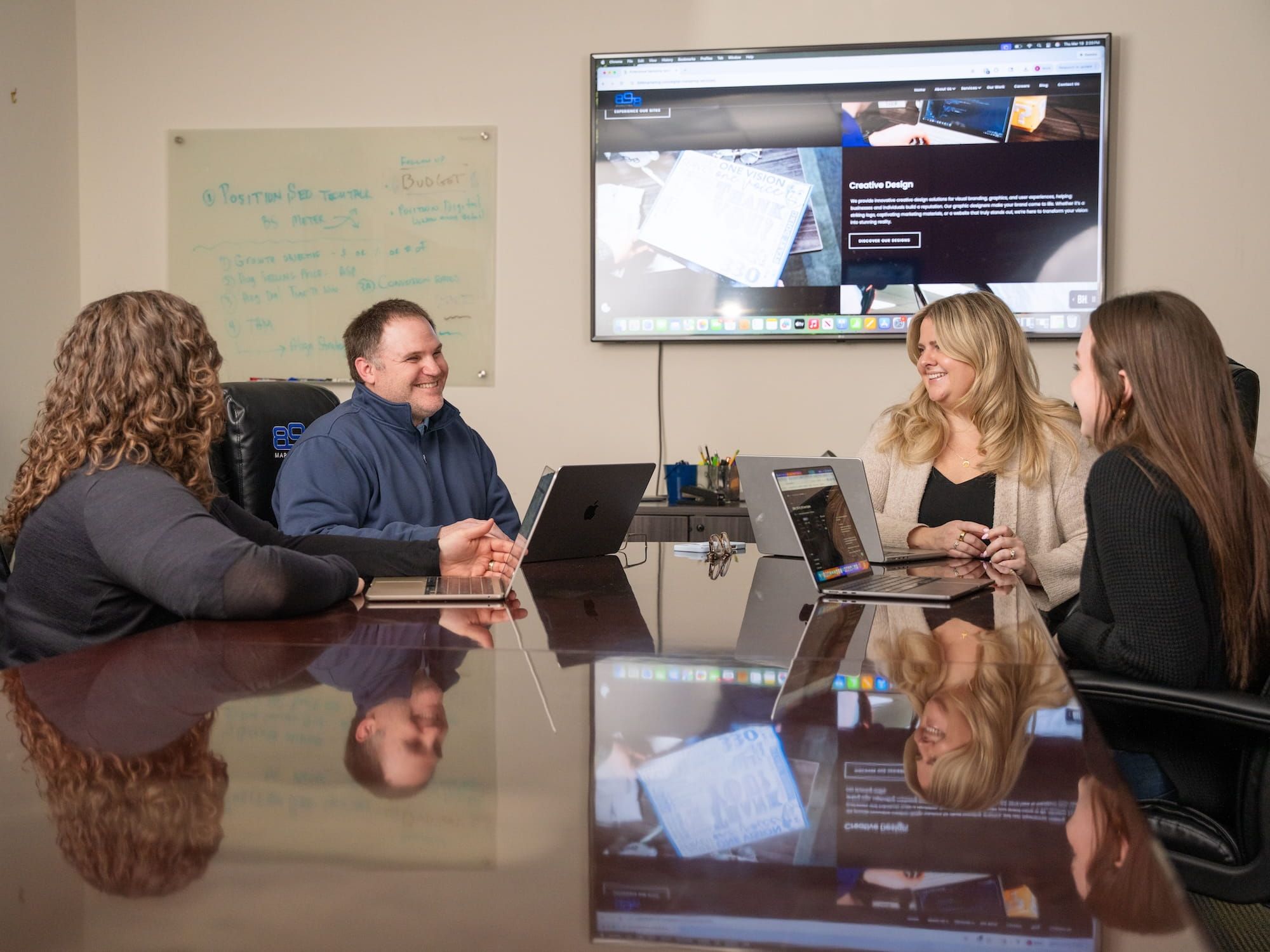 Four members of the 898 Marketing team sitting at a conference room table.