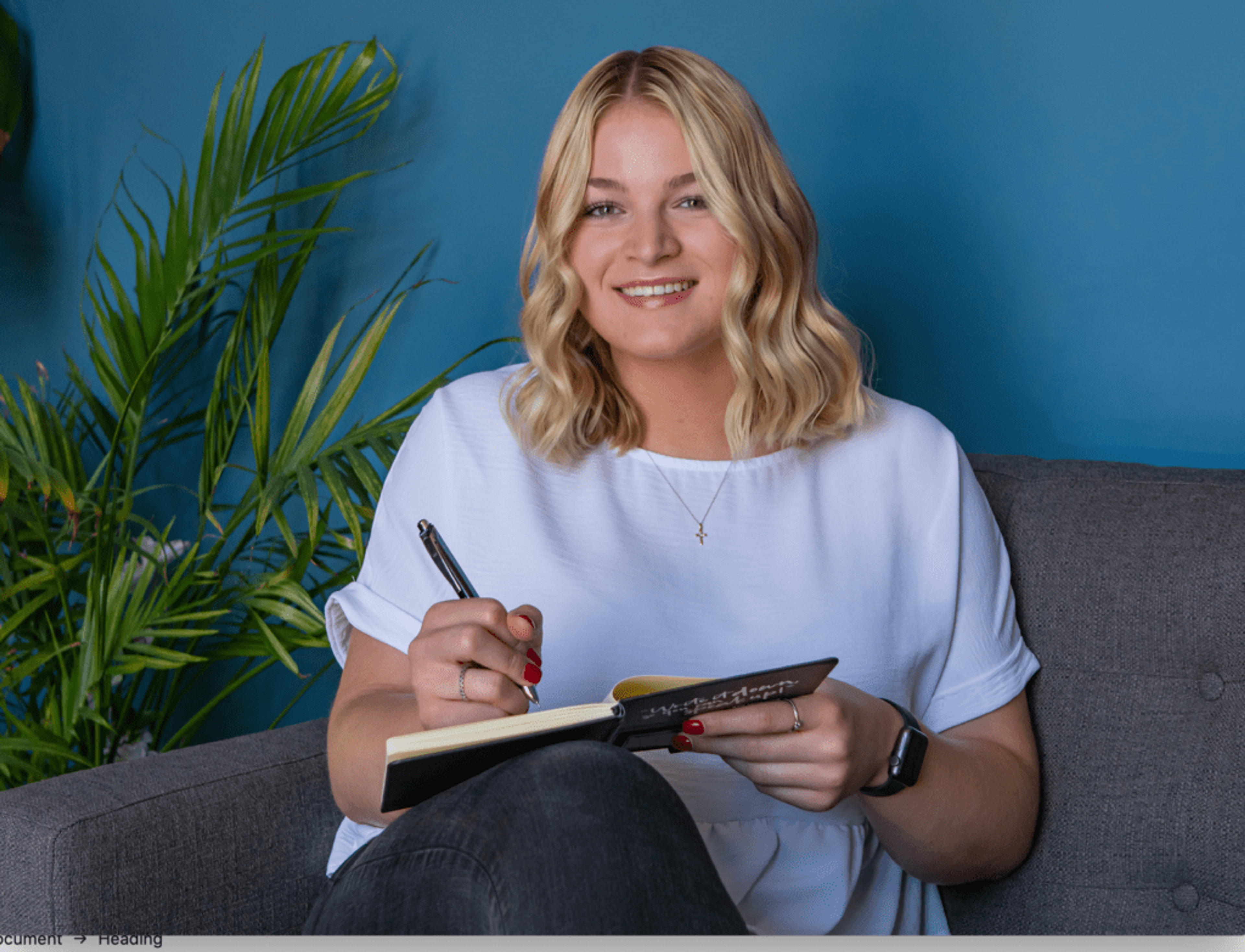 Marketing intern holding journal, smiling while sitting on couch