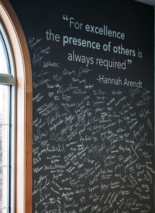 Signature wall at the 898 Marketing office in Canfield. The quote on the wall states "For excellence the presence of others is always required"