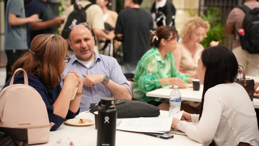 Attendees in conversation around a table between sessions.