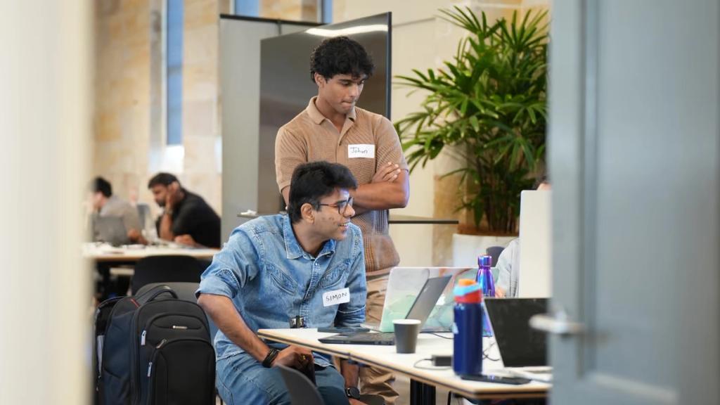 A mentor talking a participant through their work at a laptop.