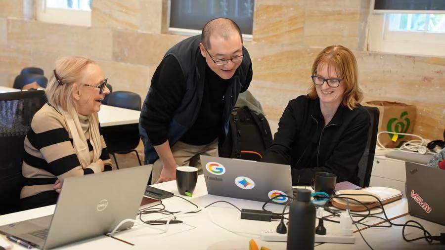 One of our team leaning in to help two people working on their laptops.