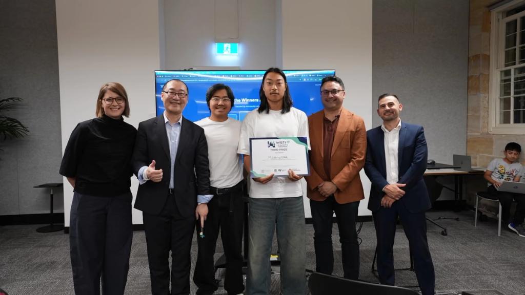 A team holding their certificate alongside the WSTI team.