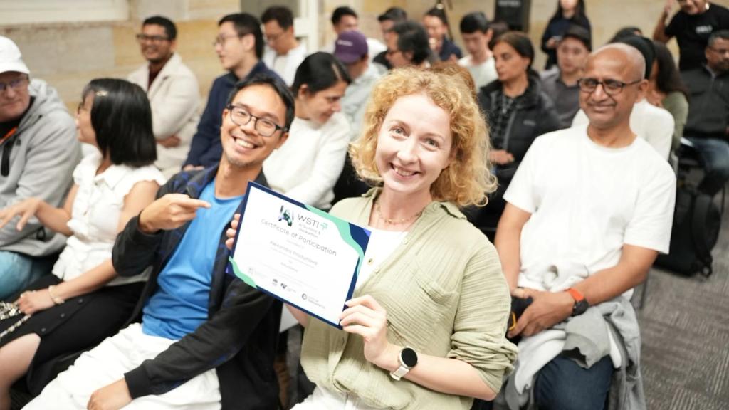 An attendee holds up her certificate in the audience