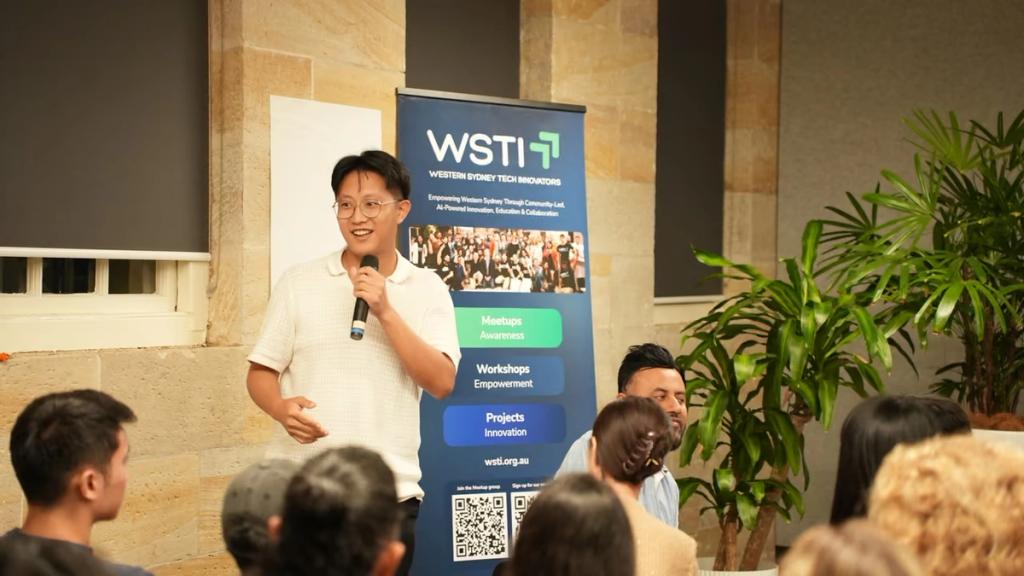 A speaker presenting with a microphone beside a WSTI banner.