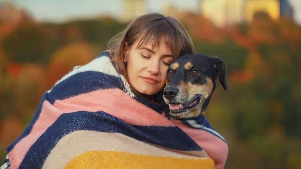 Woman Hugging Her Dog With a Blanket Around Them
