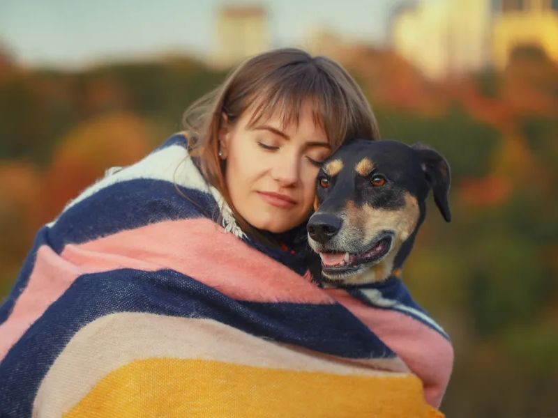 Woman Hugging Her Dog With a Blanket Around Them