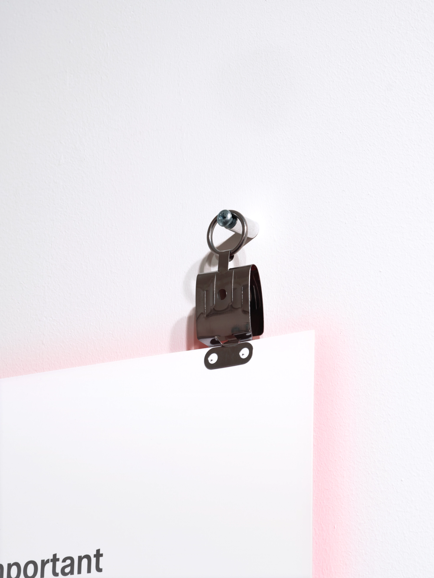 A close-up photograph of a fixing method for a text panel, using large stainless steel photo film clips.