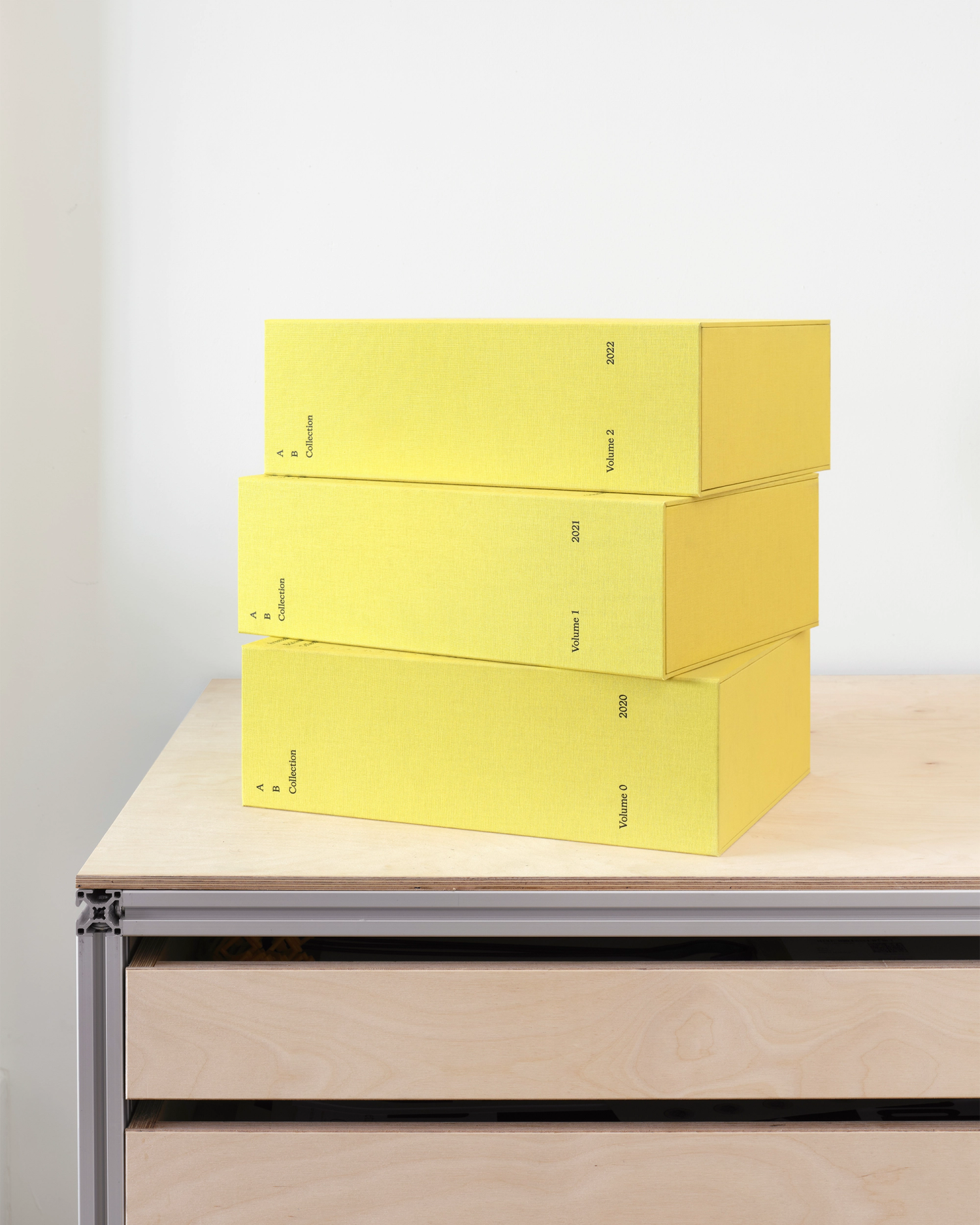 Photograph of a stack of yellow clothbound boxes on top of a plan chest