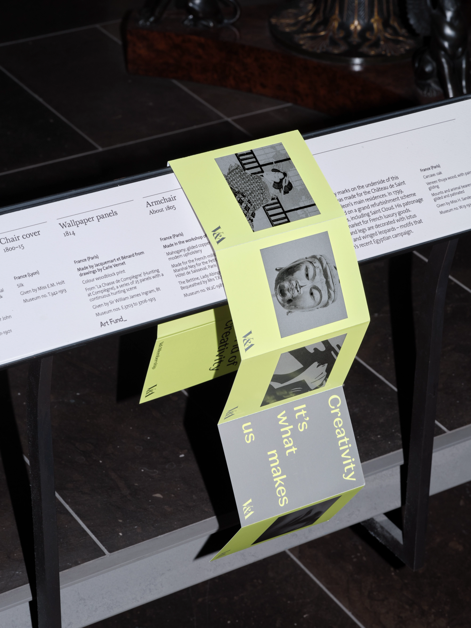 Photograph of a neon yellow and grey leaflet draped over a white railing in a dark room.