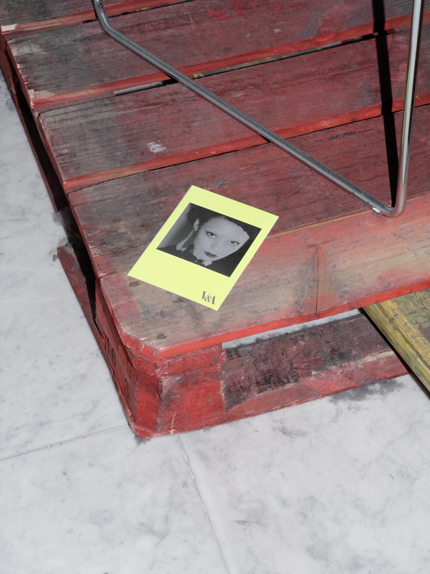 Photograph of a small neon yellow postcard on a red pallet.