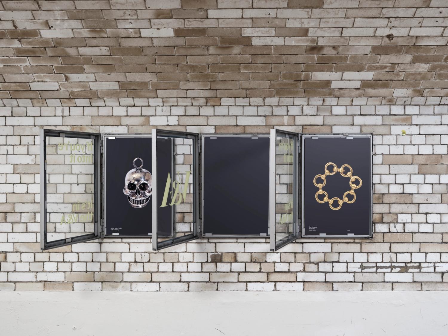 A set of three black posters in glass cases along a tiled wall of an underground tunnel.