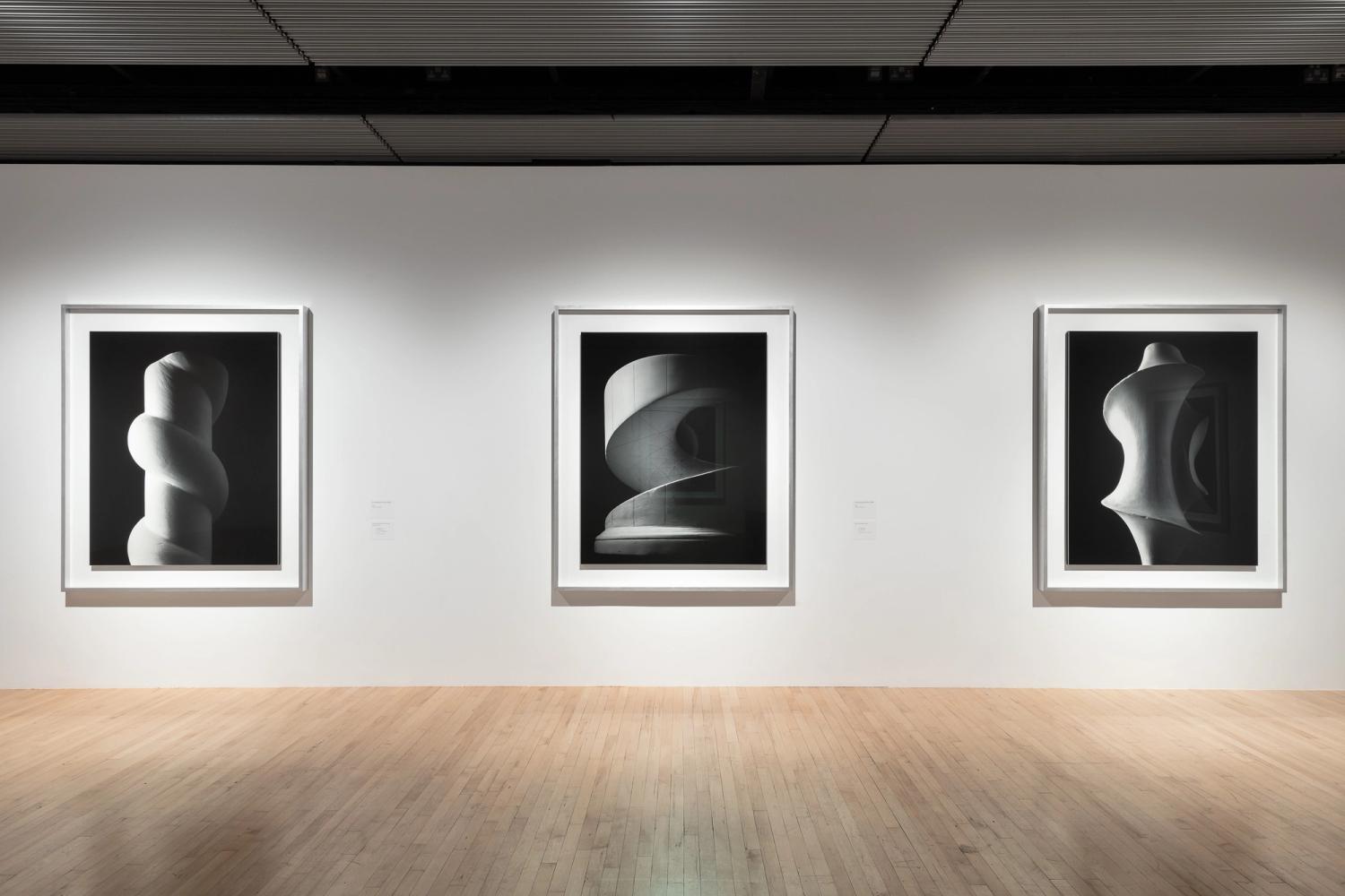 Photograph of a gallery wall with three large framed black and white abstract photographs