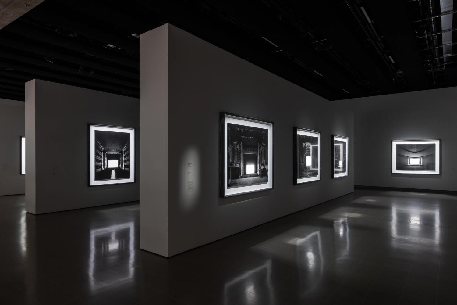 Photograph of gallery showing text caption next to photographic works by Hiroshi Sugimoto