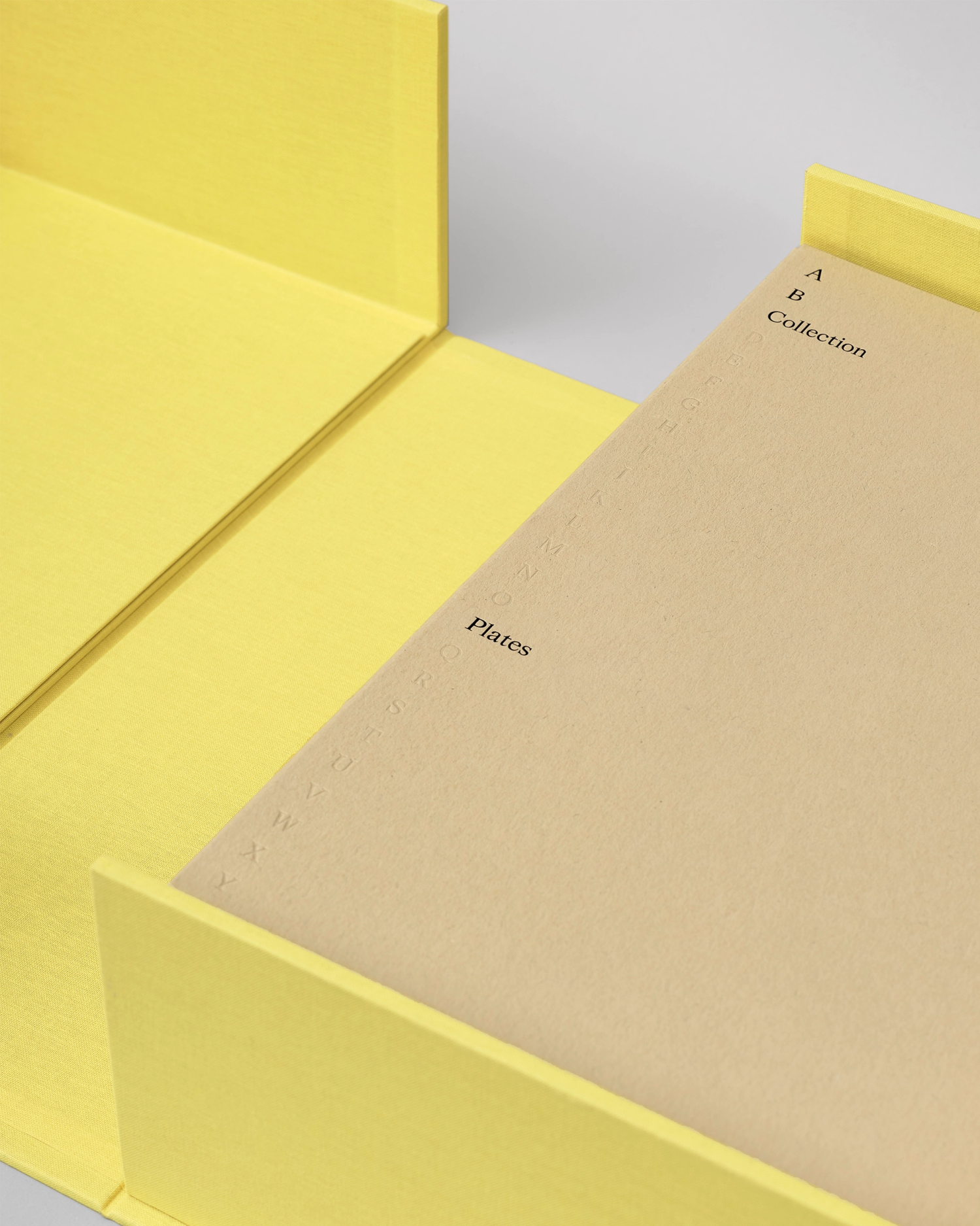 Photograph of beige folder within yellow box showing embossed typography details