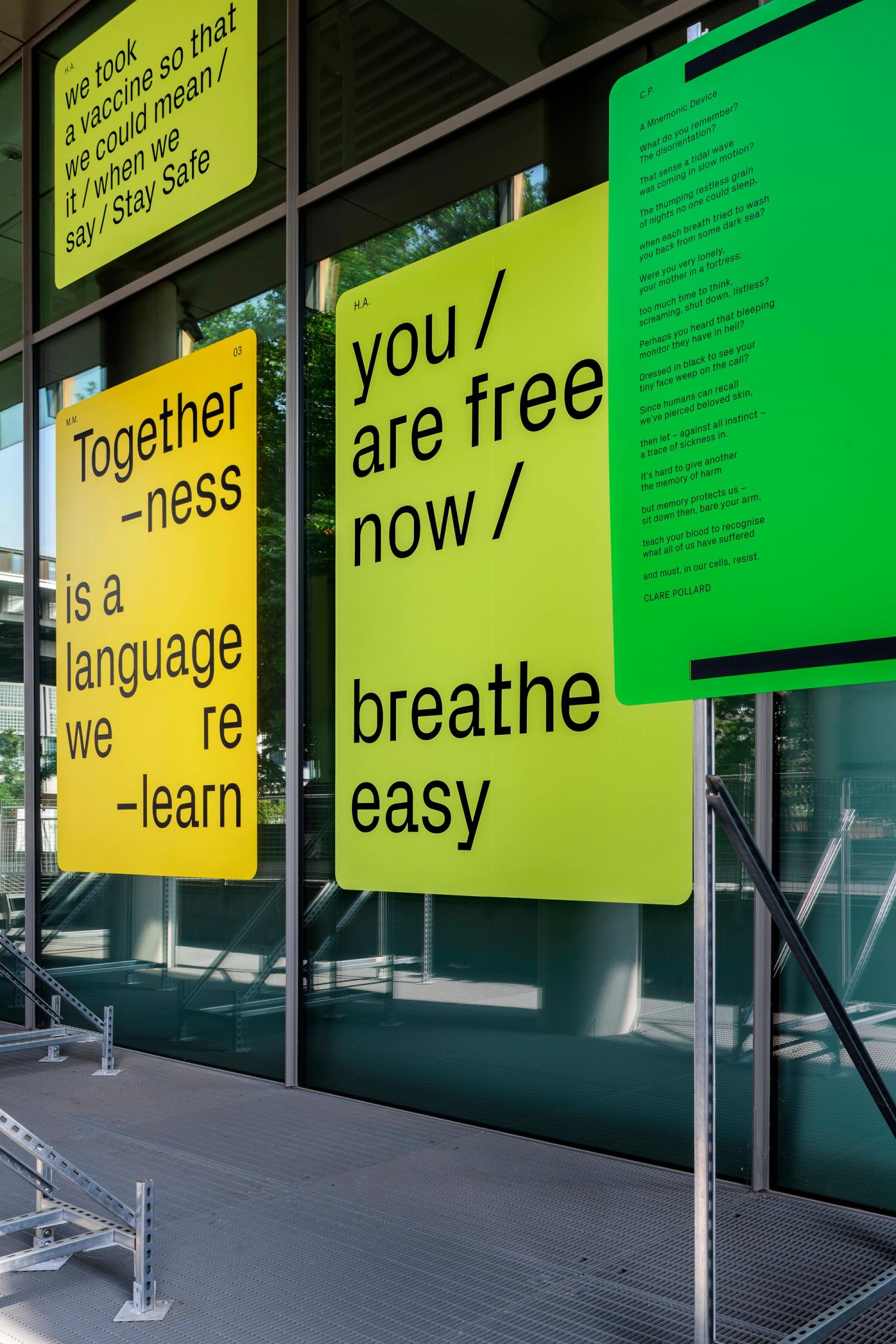 A display of yellow and green panels fixed to structures on a building's exterior, each panel has a piece of text printed on it in black type.