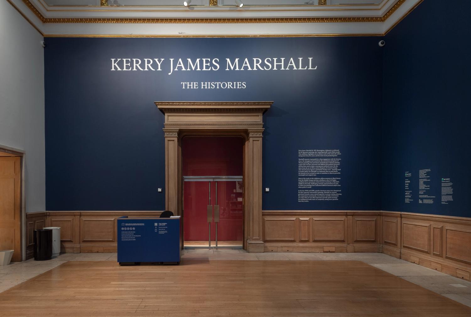 Exhibition entrance with dark blue walls, wooden doorway, and signage for Kerry James Marshall's "The Histories."