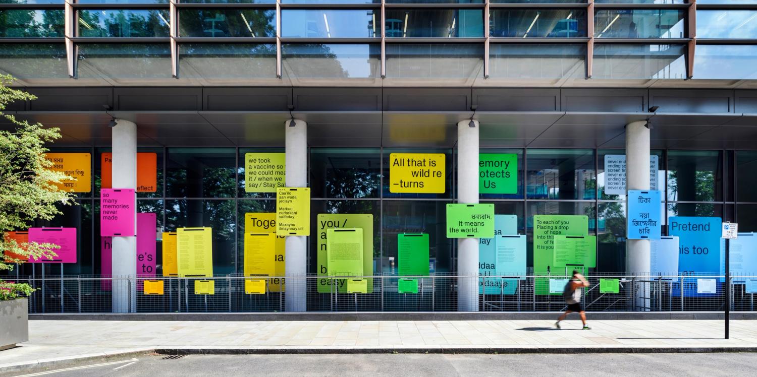 A display of brightly-coloured text panels fixed to the exterior windows, columns and railings of a building.