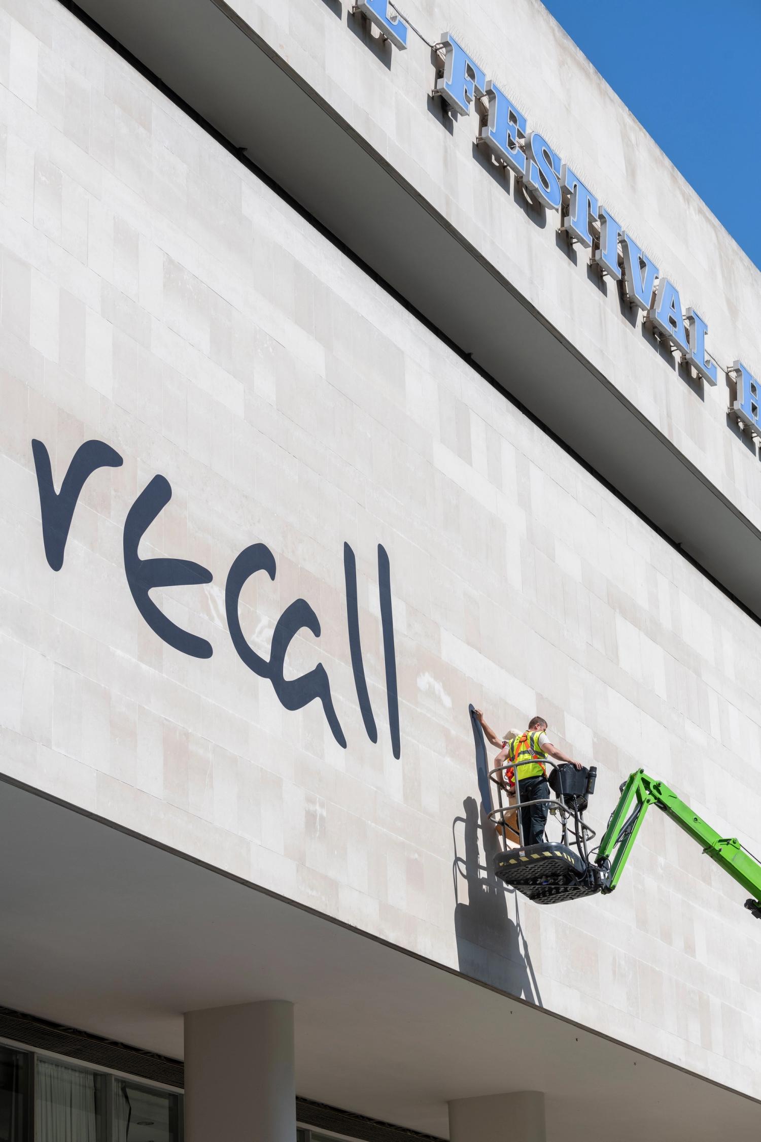 Photograph of two men installing large-scale vinyl type on the Southbank Centre's facade