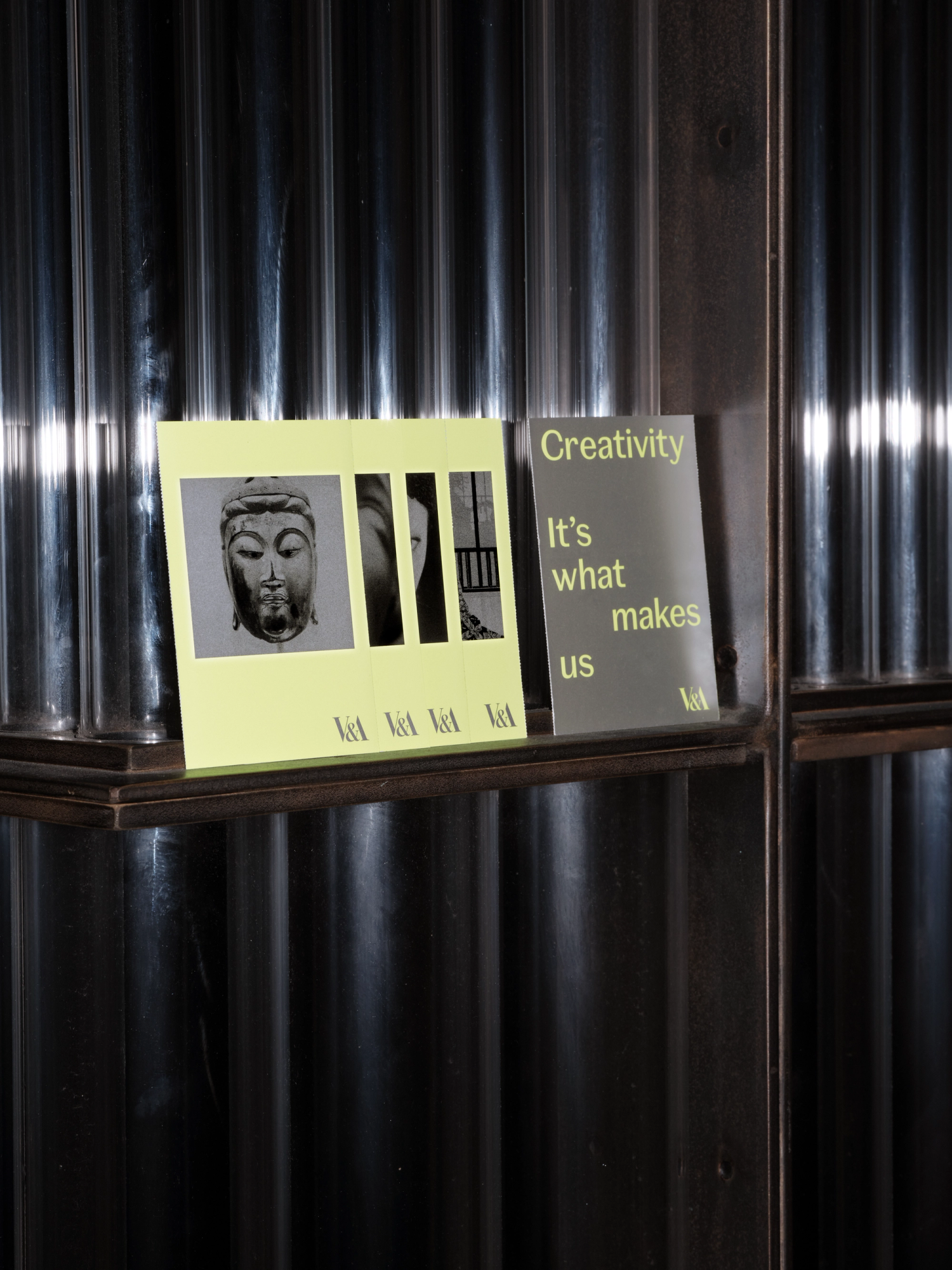 Four neon yellow booklets lined up on a shelf against a glass showcase.