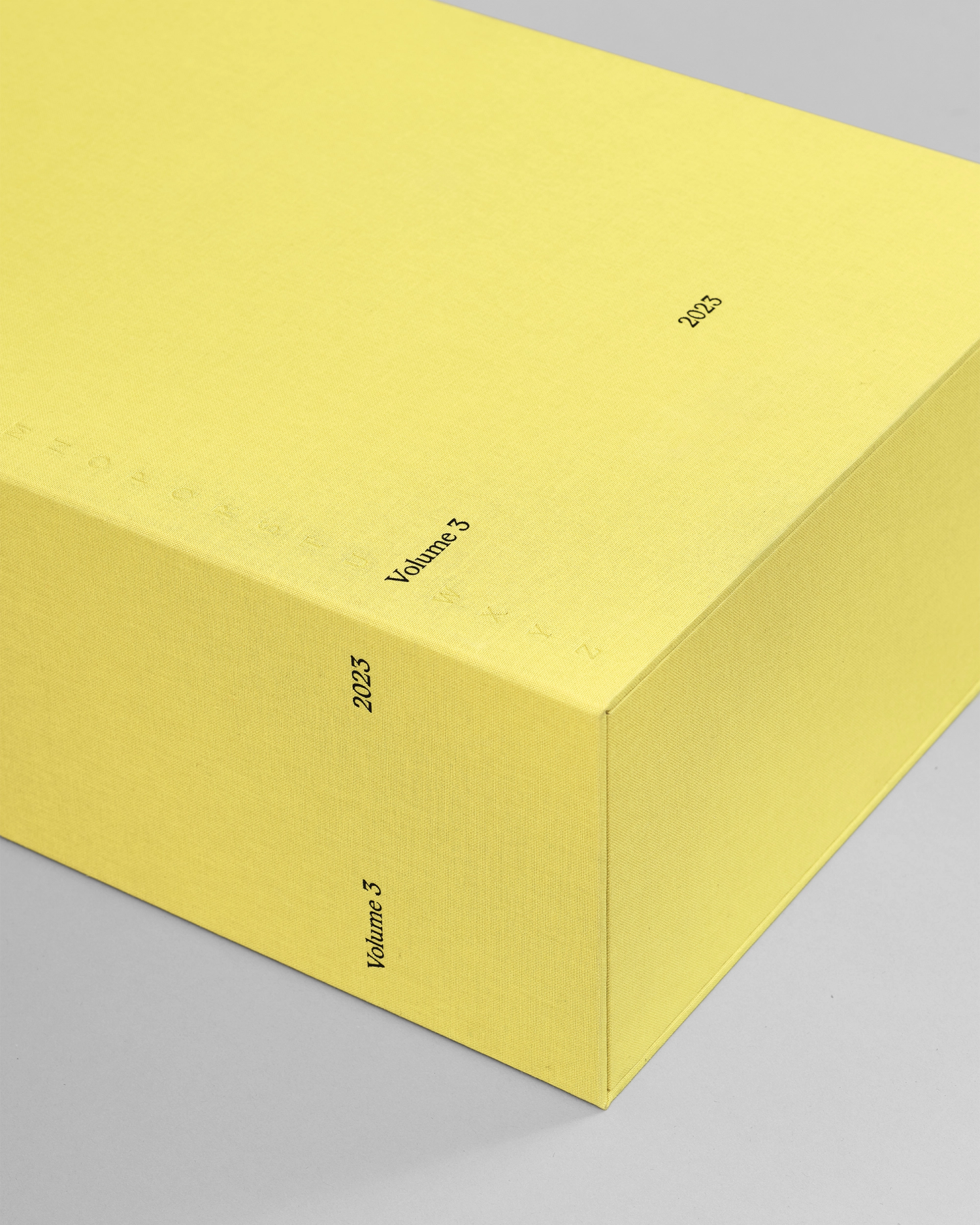 Photograph of the corner of a yellow portfolio box with typographic embossed and foiled details