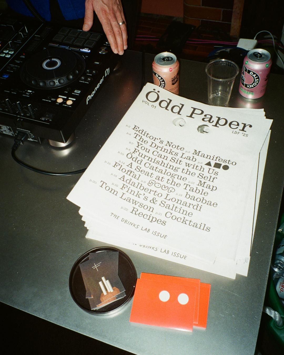 Ödd Paper with eye holes on a table, beside a DJ controller and drinks cans, at LDF 2025 Drinks Lab event.