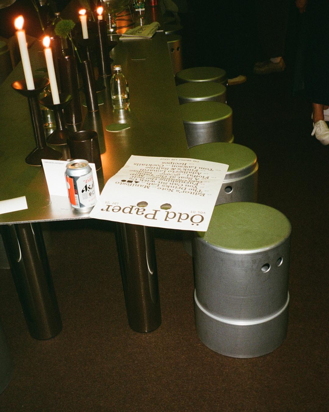 A sheet of Ödd Paper with eye holes is placed on a metallic table surrounded by silver 'Peepers' stools.
