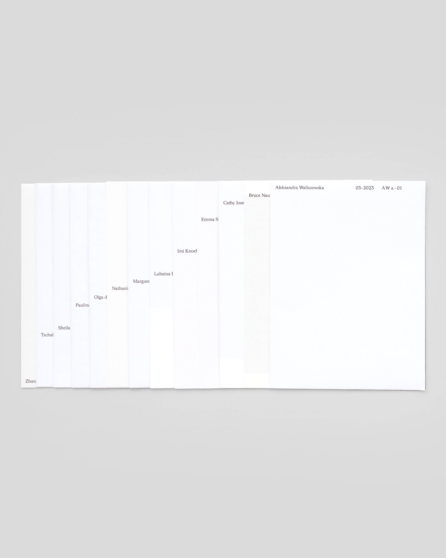 Photograph of a spread of folded sheets of white paper showing graphic type detail