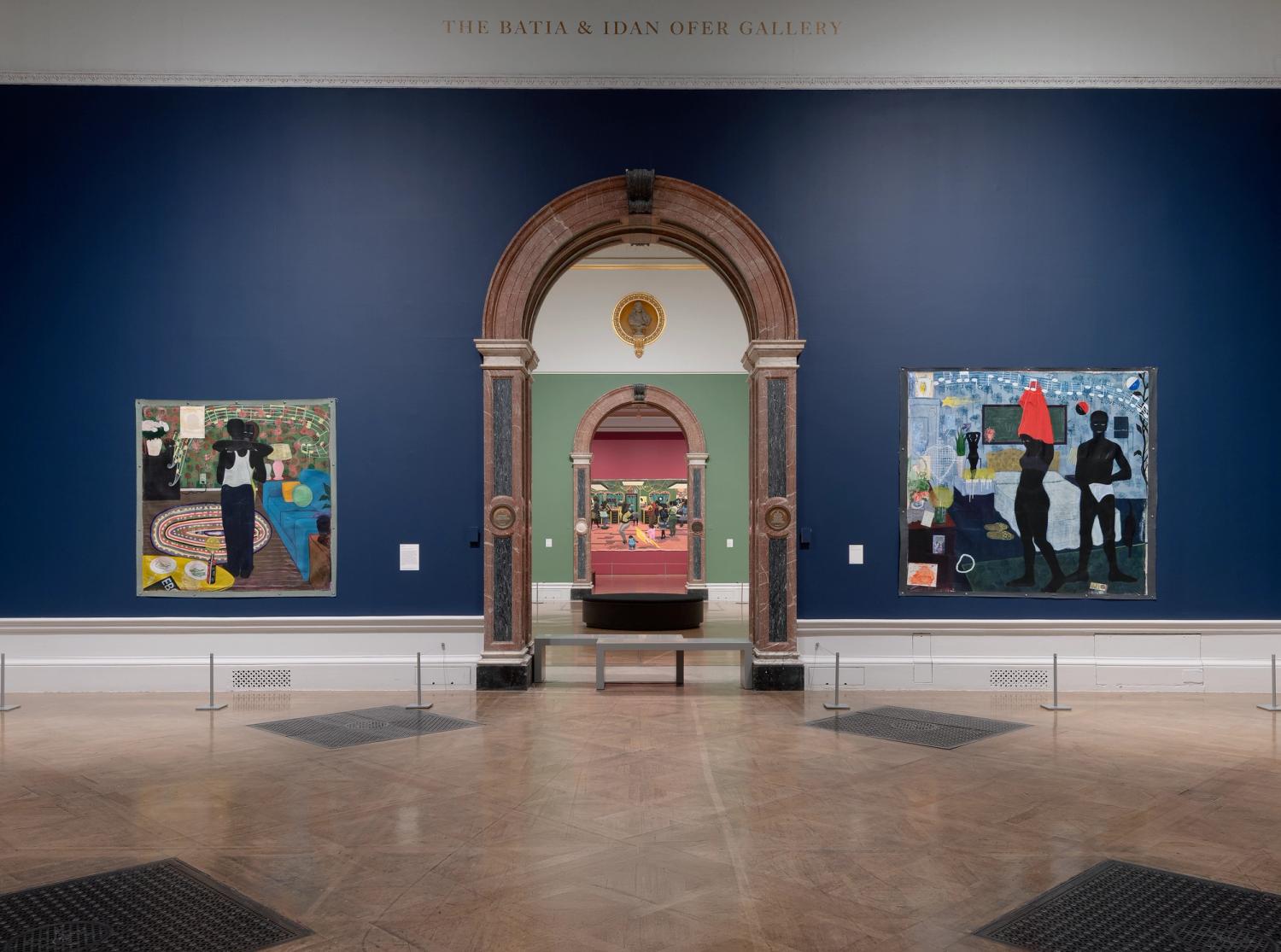 Gallery with two paintings on a dark blue wall, flanking an ornate archway leading to another exhibit room.