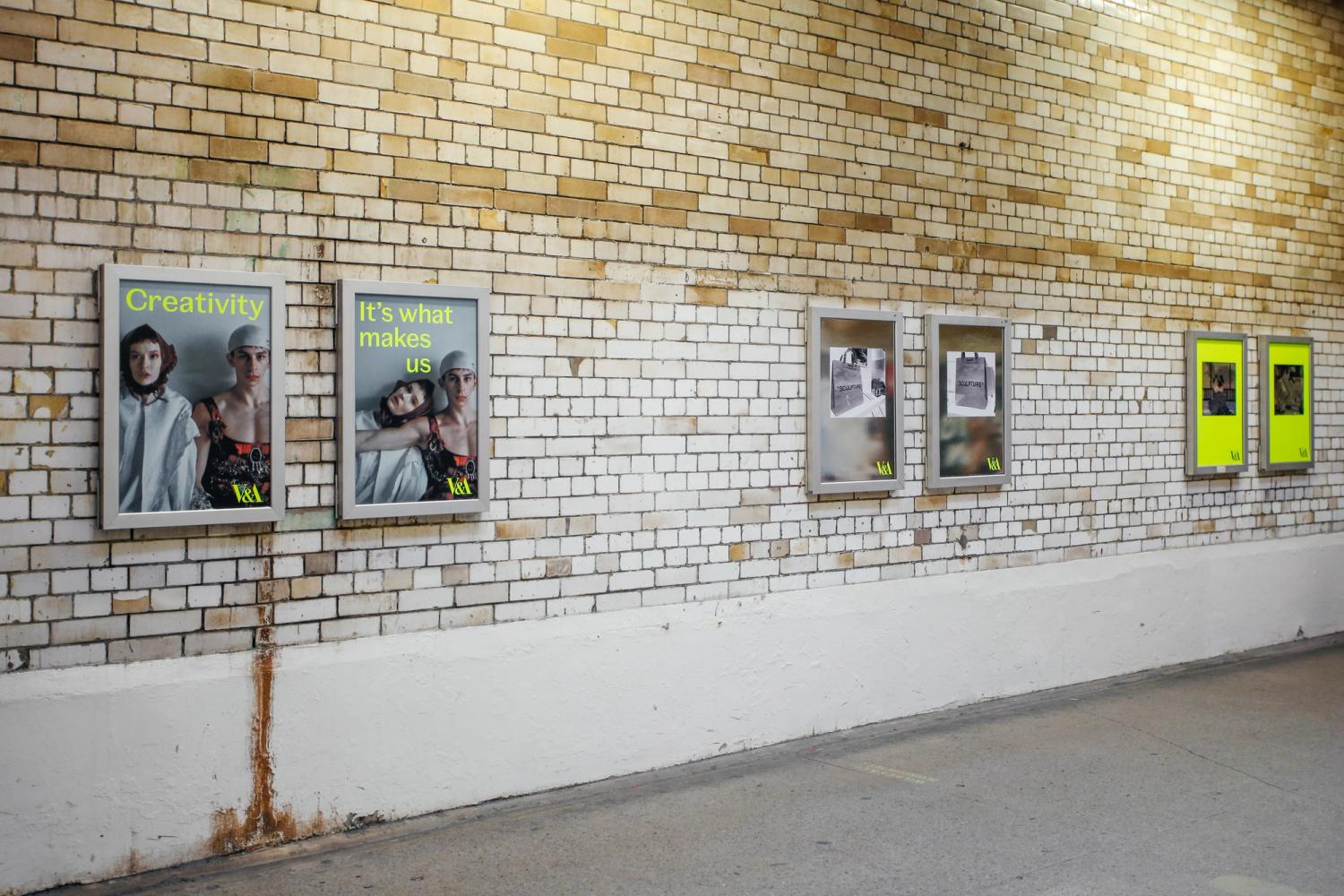 V&A posters in subway tunnel frames on a brick wall, featuring models and text "Creativity: it's what makes us."