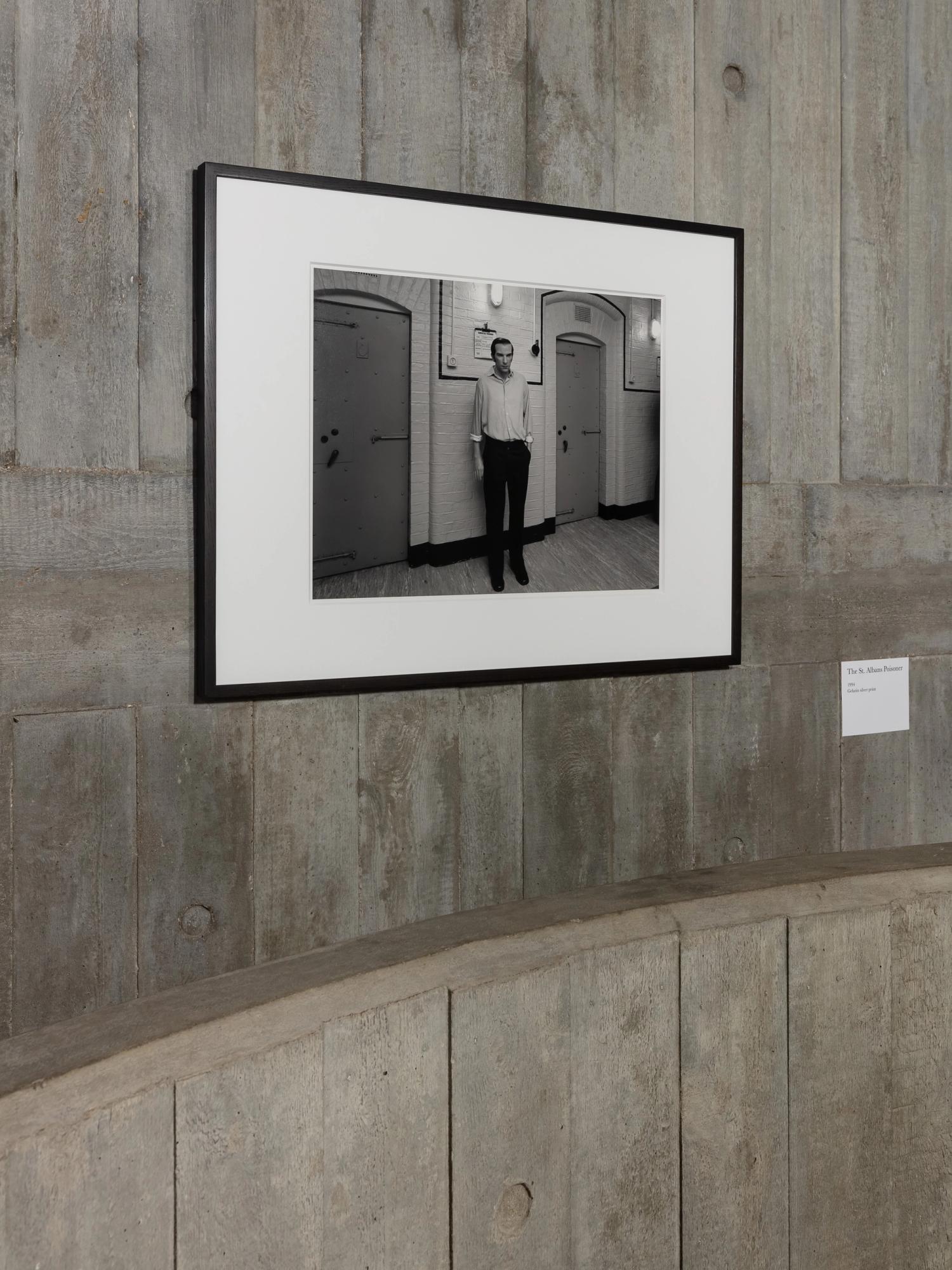 A photograph black and white framed photograph on a textured concrete wall with white image caption beside