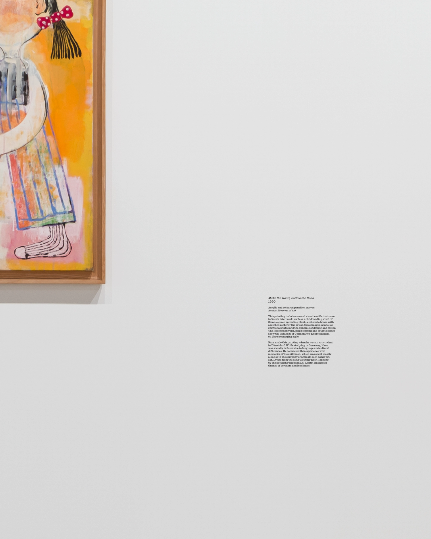 A detail shot of a caption with extended artwork information sits to the bottom right of a colourful framed artwork.