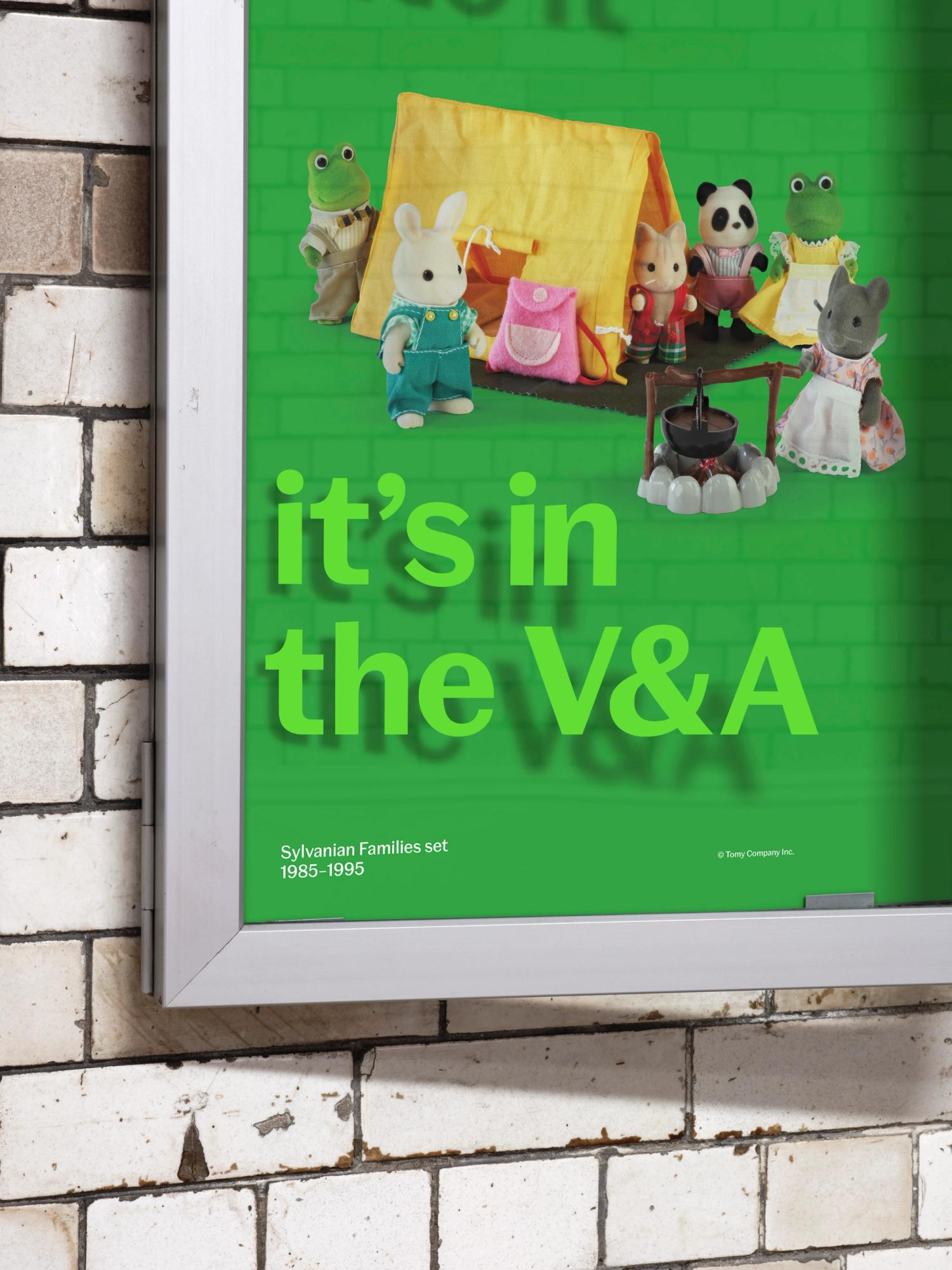A close-up detail of a green poster behind the glass of a poster case, showing the shadow from the text on the glass and an image of Sylvanian Families printed