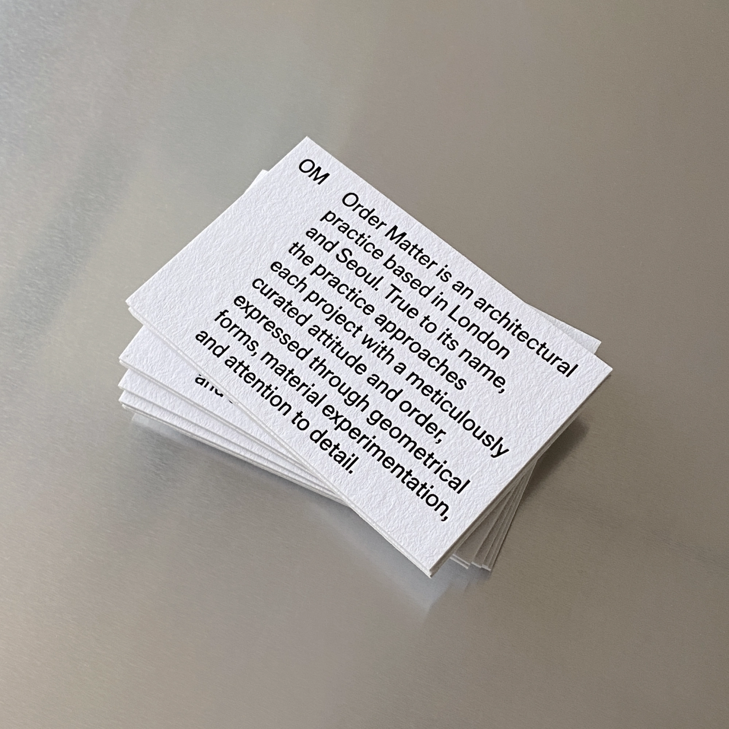 Stack of white business cards with black type on aluminium surface