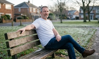 Man in white t-shirt sitting relaxed on a park bench in winter, calm after resolving his debts