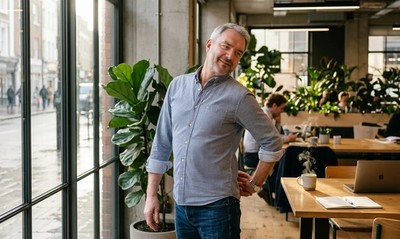 A 60-year-old man stretches by a sunny window in a co-working space on a winter morning.
