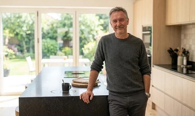 Man in his fifties standing in sunlit new-build kitchen, contractor mortgage homeownership