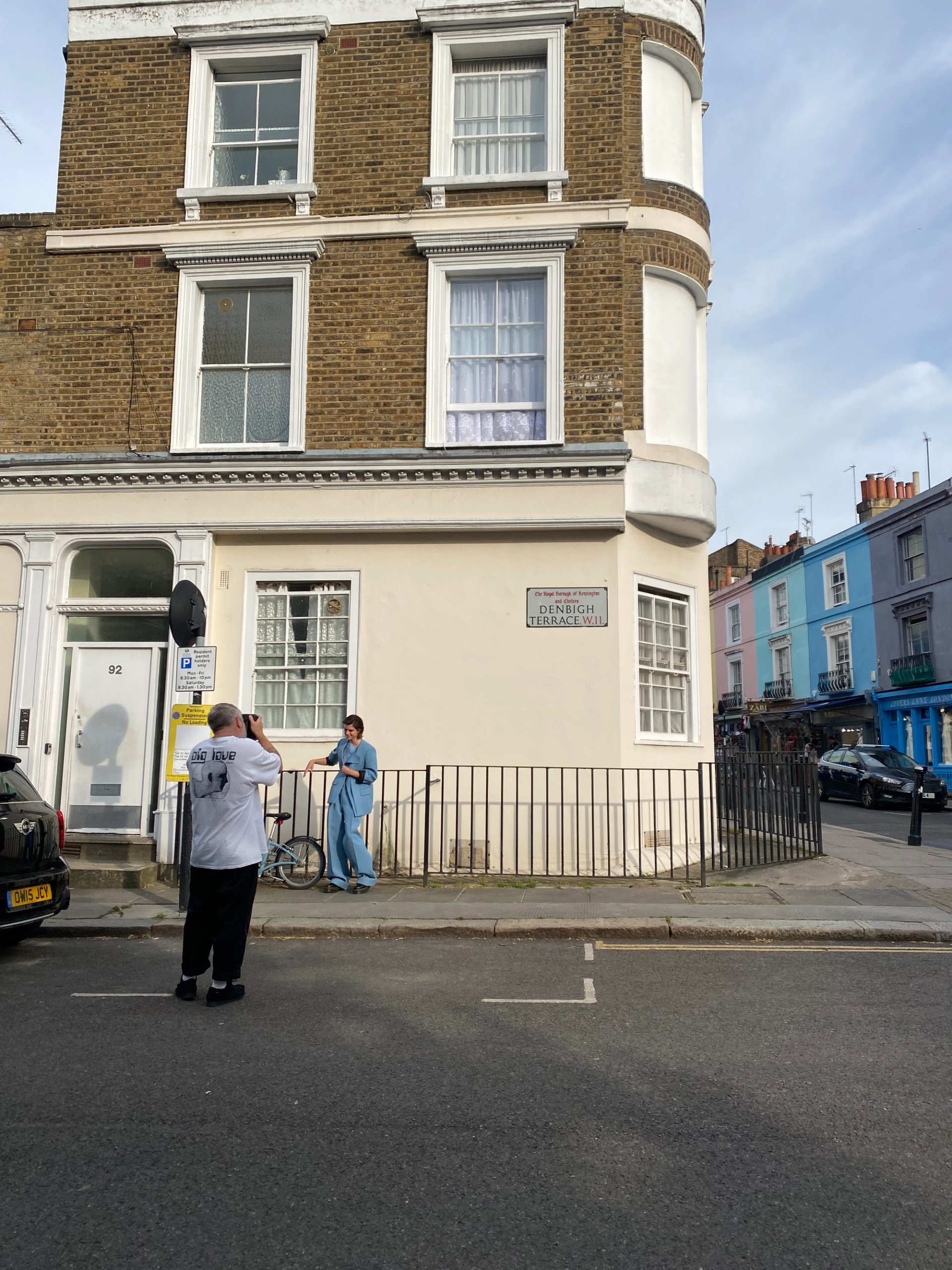 Photographer shooting model in blue jumpsuit on Denbigh Terrace with colourful Notting Hill houses behind