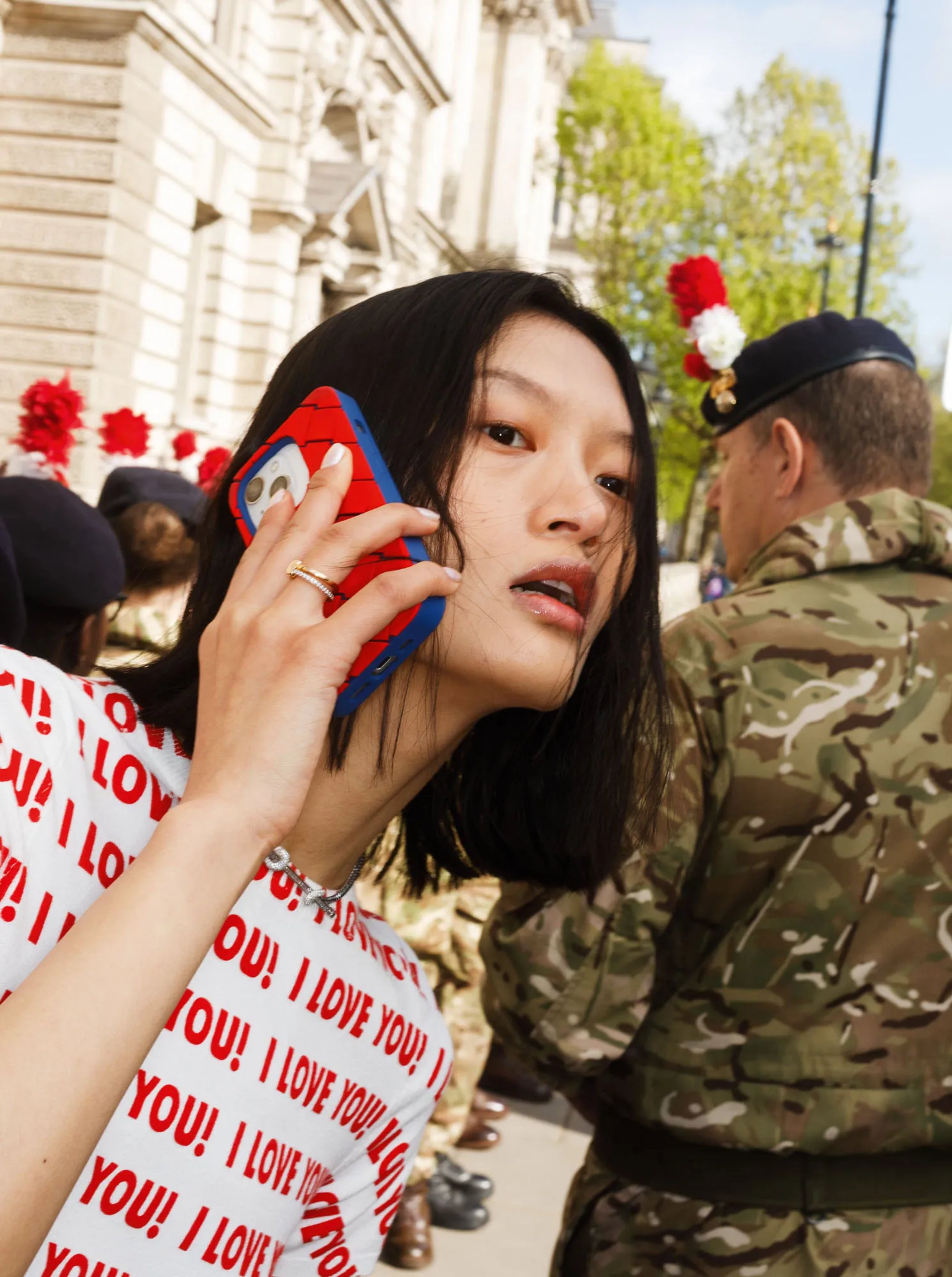 Model on phone with Spider-Man case wearing I Love You print tee near London soldiers