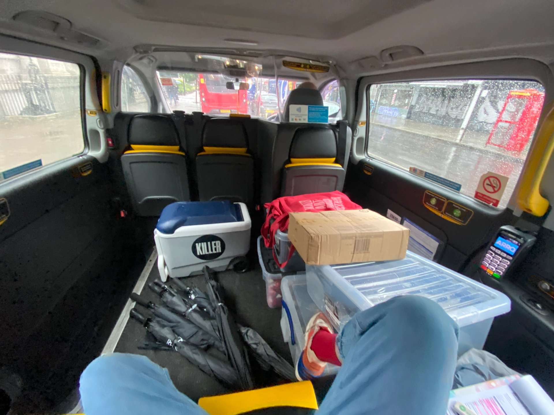 Back of London black cab loaded with KILLER branded cooler box, umbrellas and production equipment on rainy day