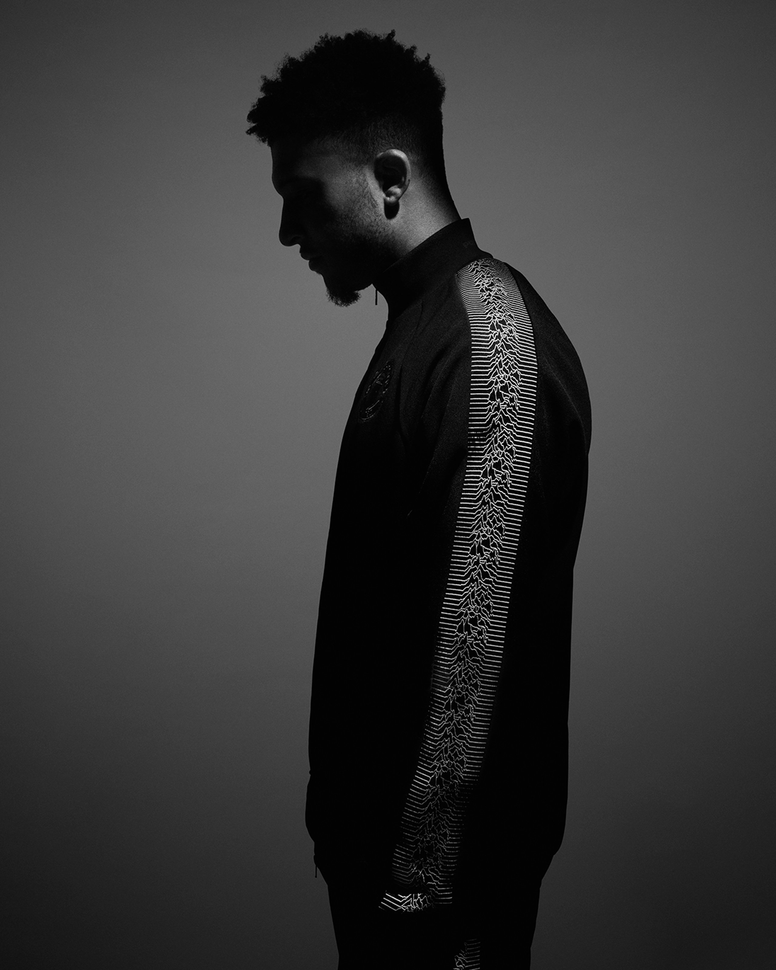 Black and white side profile showing Joy Division Unknown Pleasures waveform detail on adidas x Manchester United sleeve