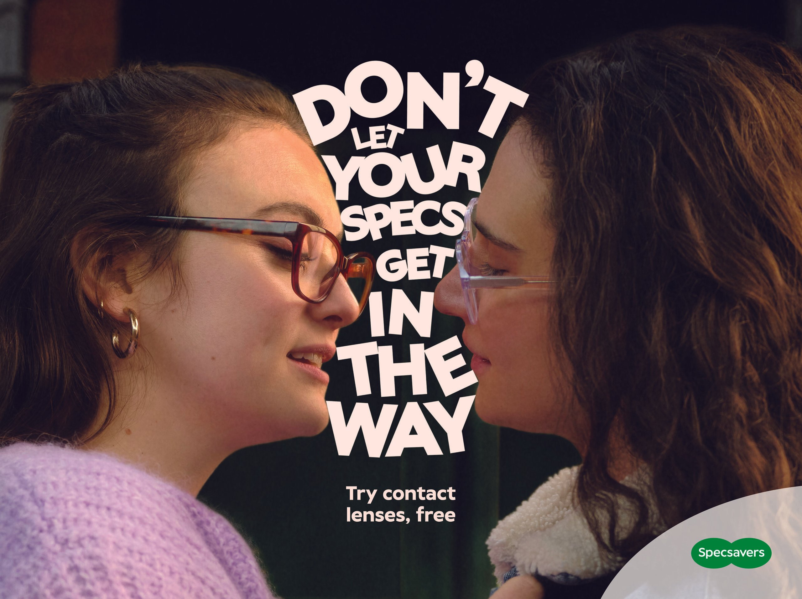 Two women about to kiss with glasses bumping and Specsavers contact lens campaign typography