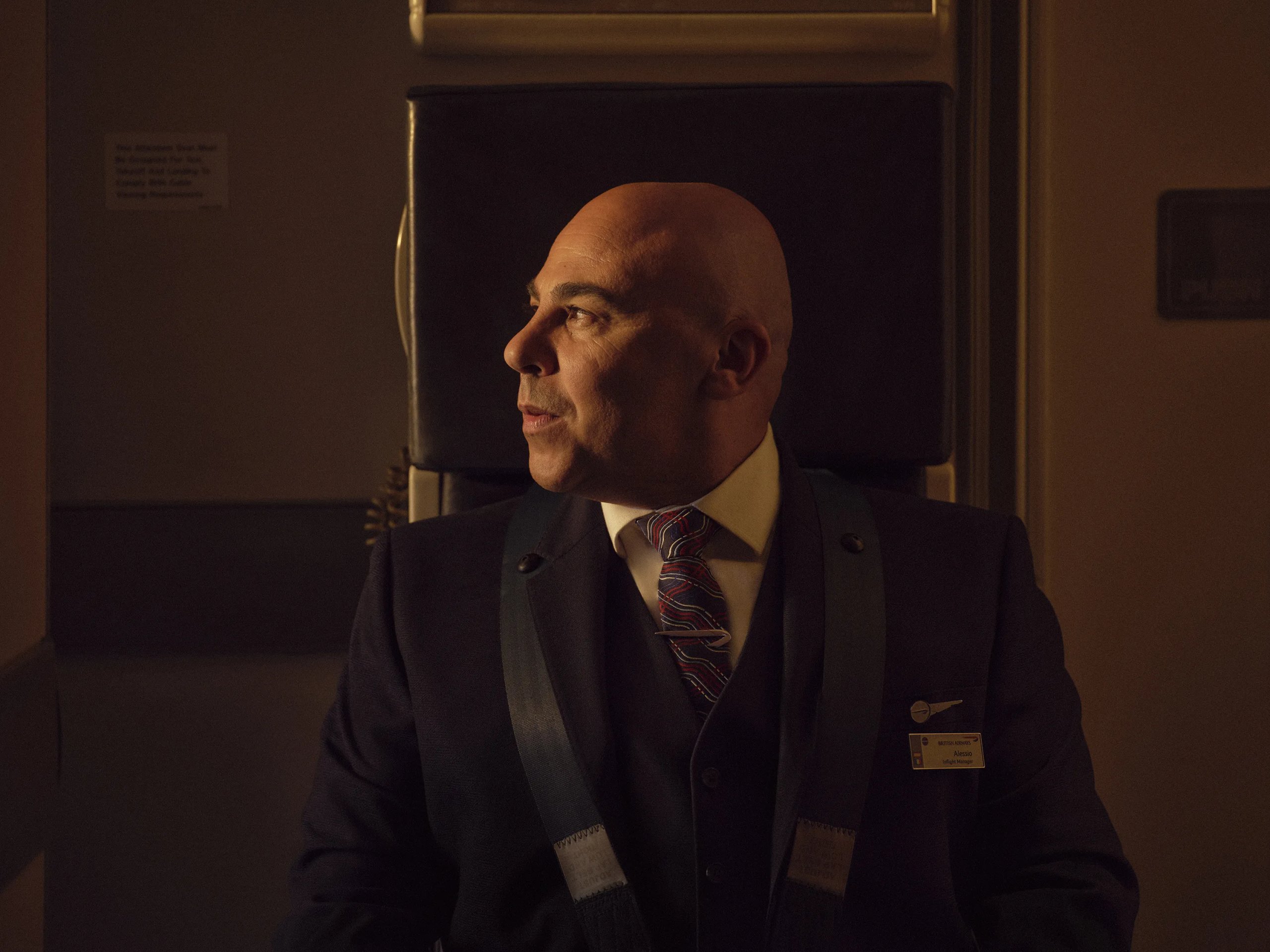 British Airways pilot in uniform seated in crew rest area with warm cabin lighting