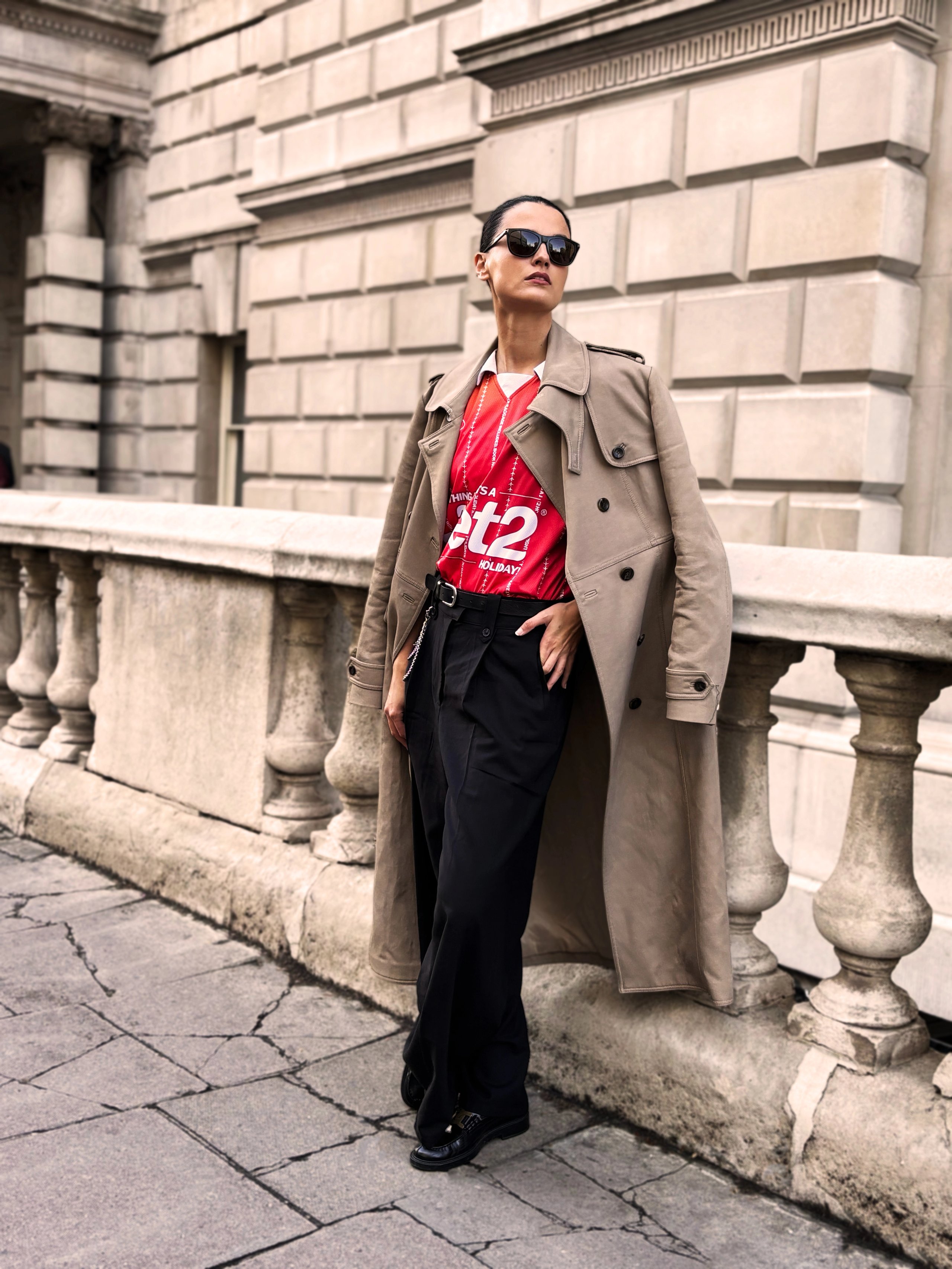 Model in beige trench coat over red Jet2 jersey with wide-leg trousers at Somerset House
