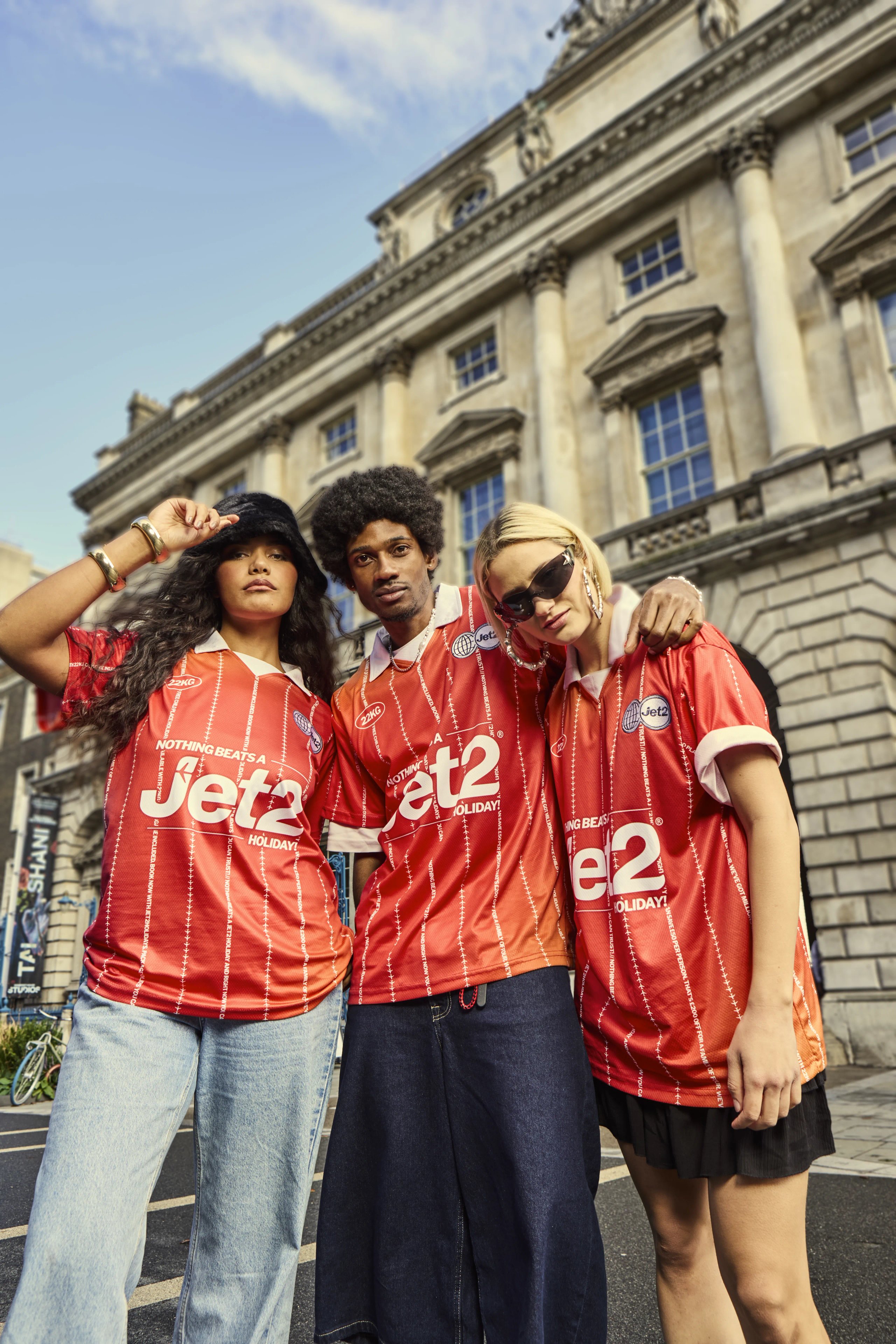 Three models in red Jet2 football jerseys posing outside Somerset House for London Fashion Week