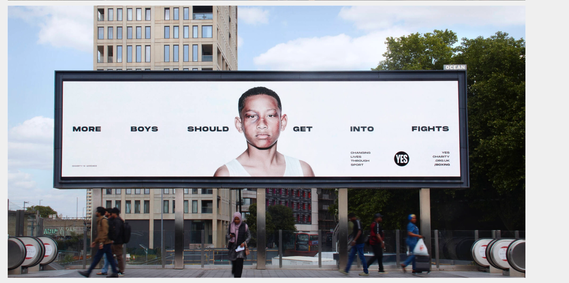 YES! charity More Boys Should Get Into Fights billboard mockup on urban street with pedestrians