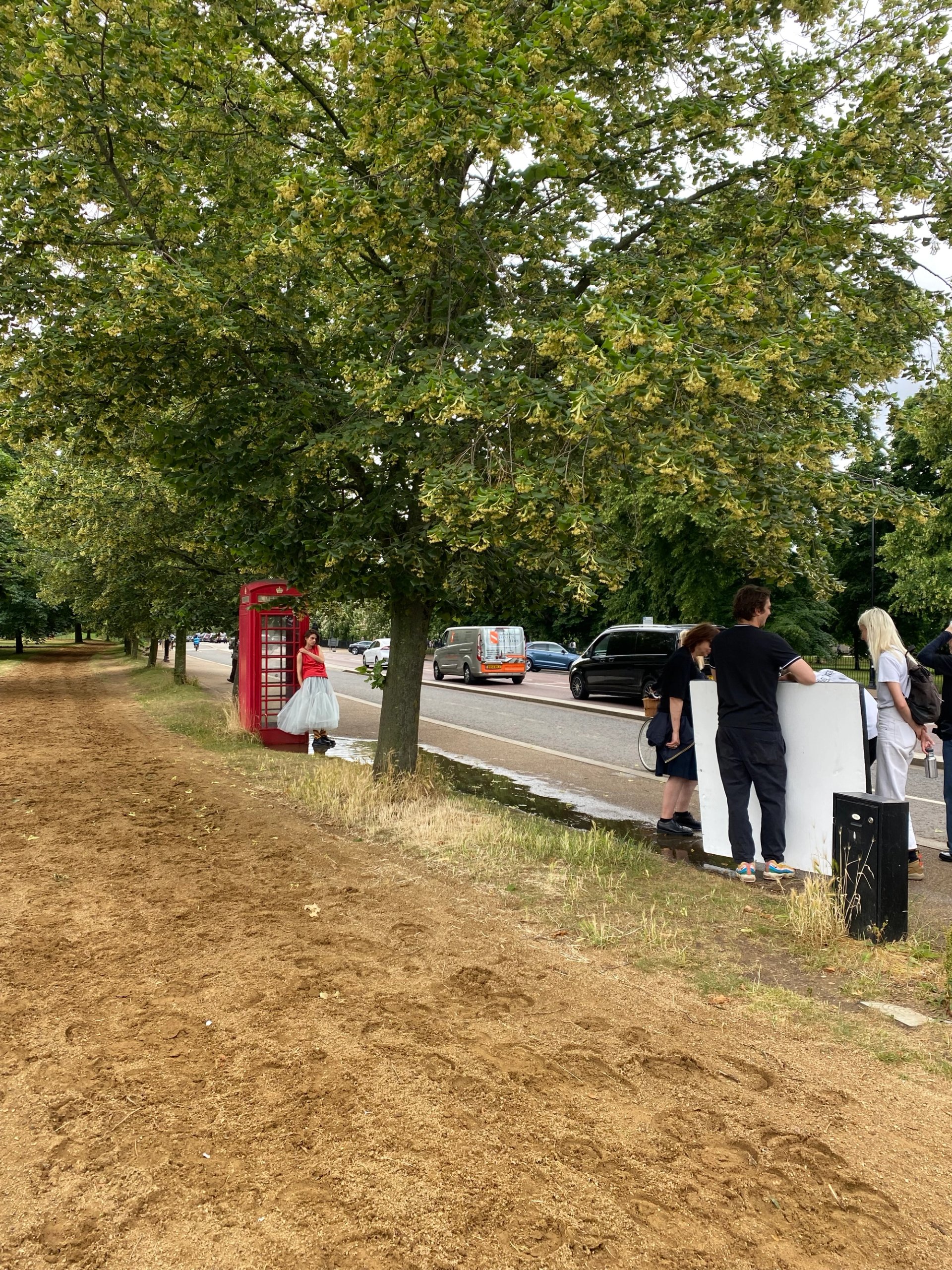 Production crew with reflector setting up shot of model by red phone box in London park
