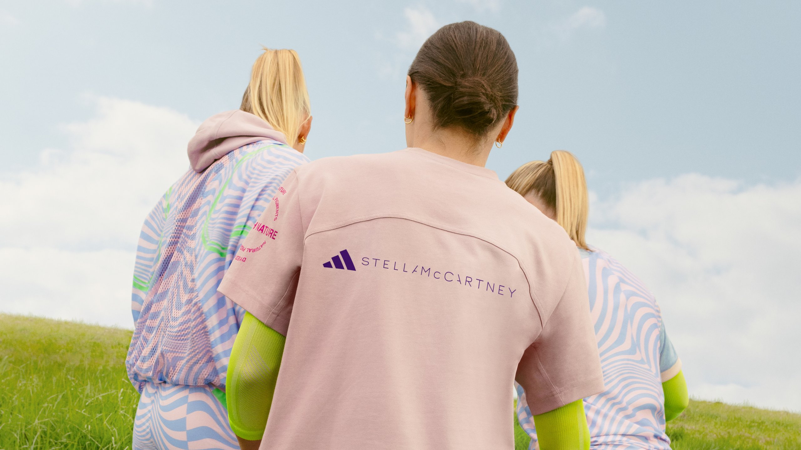 Three Arsenal Women players from behind showing adidas x Stella McCartney branding on pink training tee