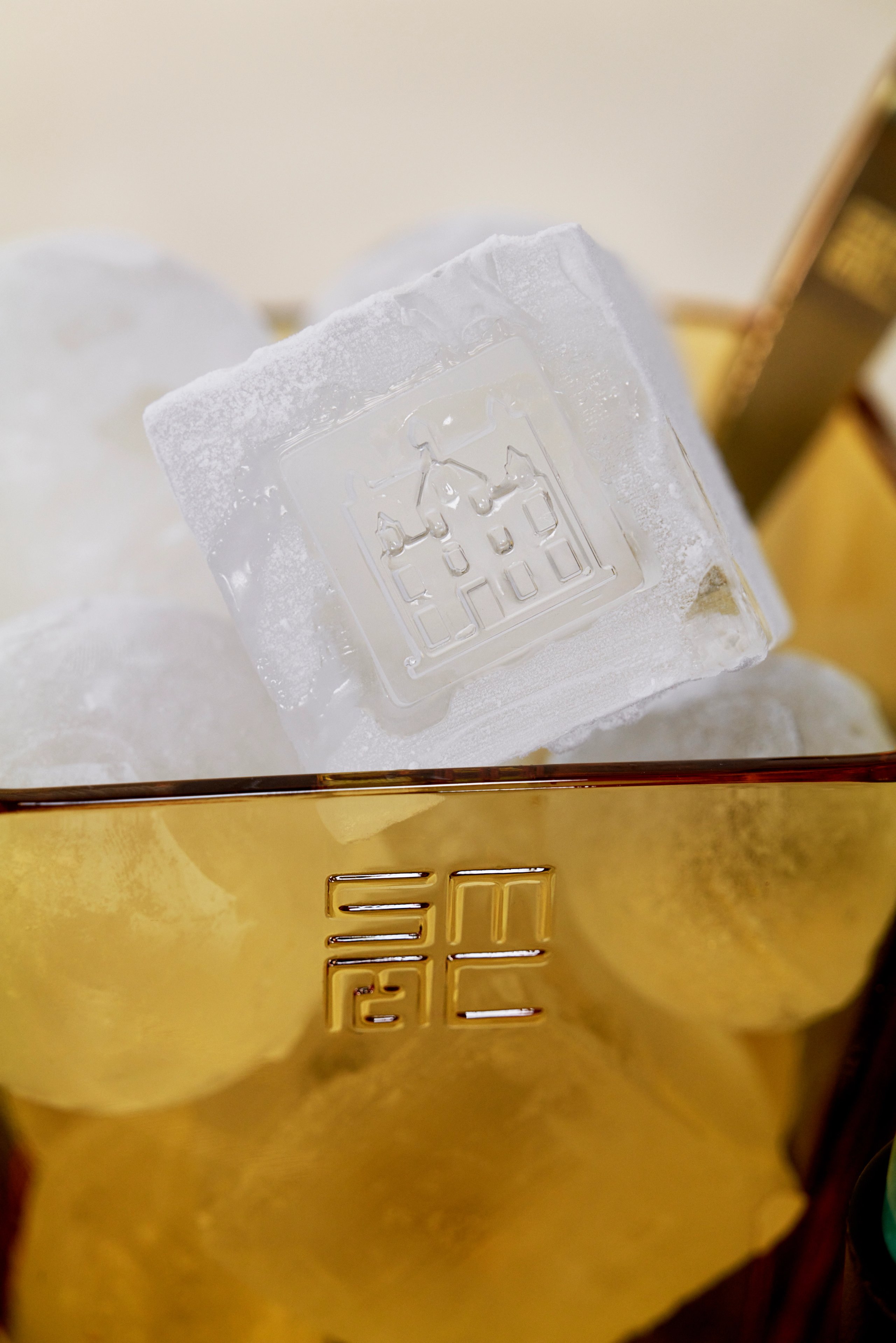 Macallan branded ice cube with distillery emblem in gold ice bucket close-up
