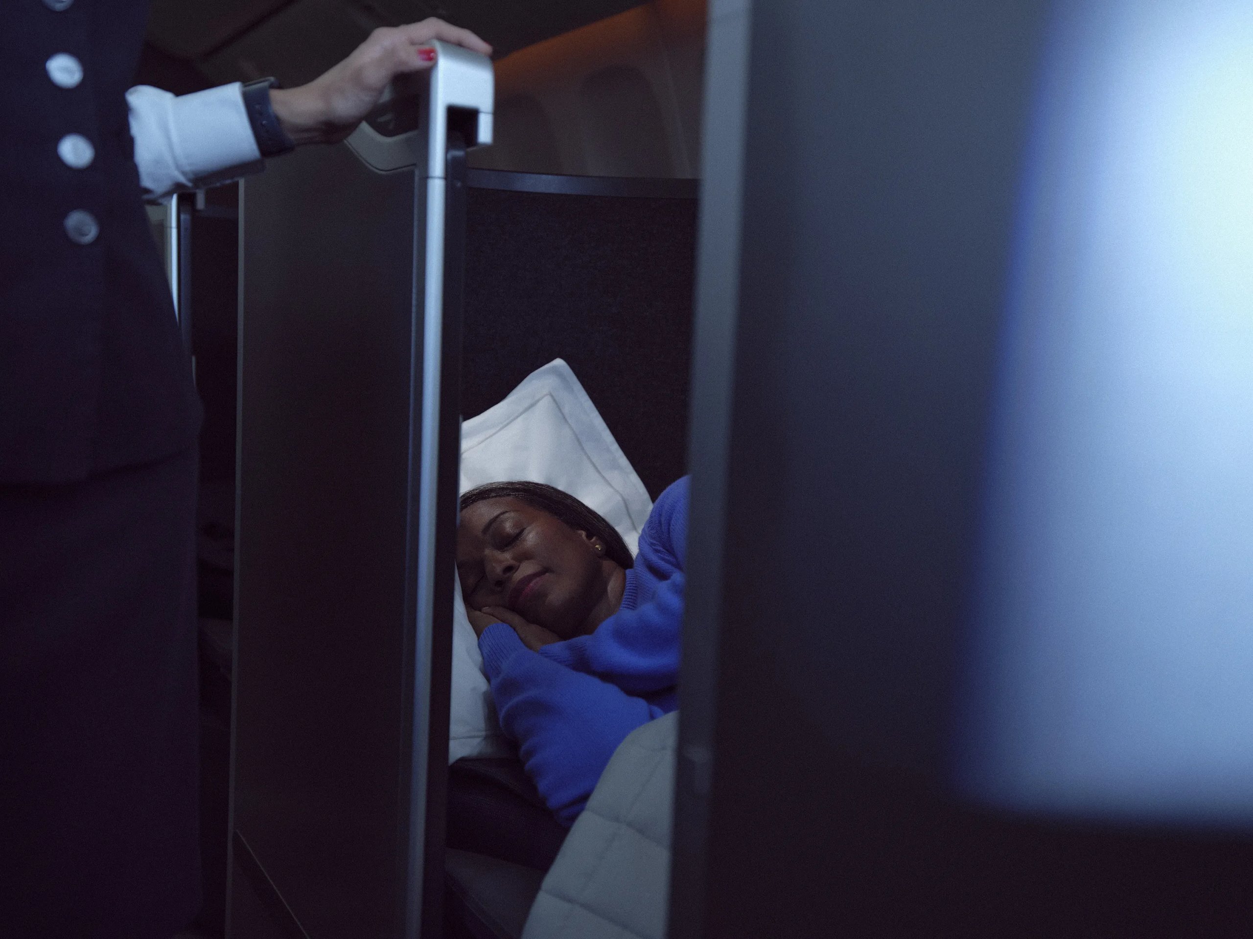 Passenger sleeping in British Airways Club Suite with crew member closing privacy door